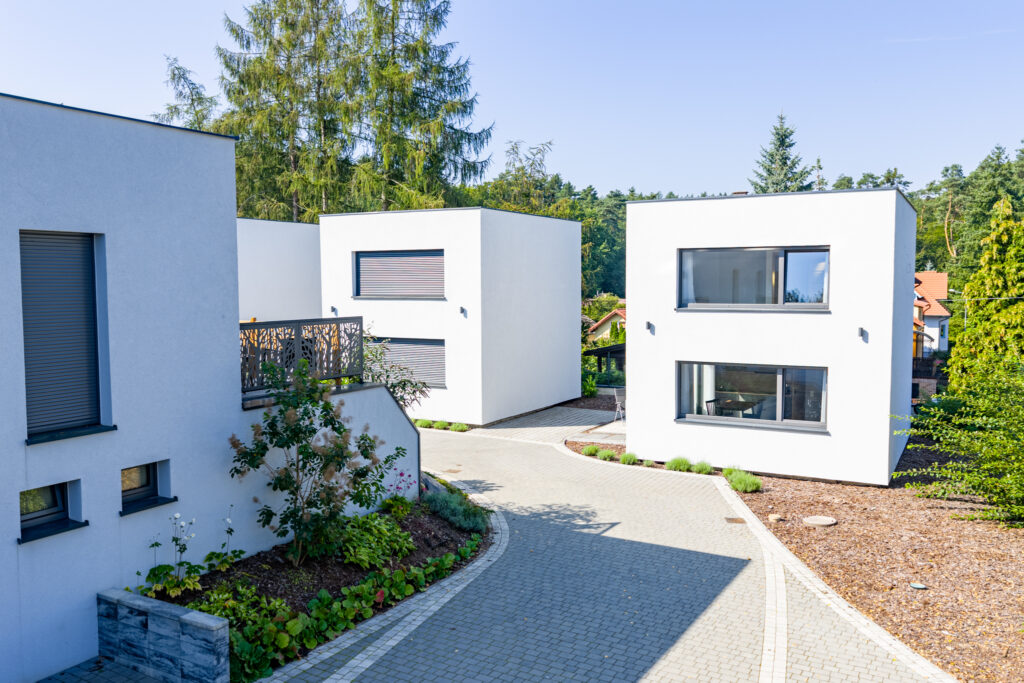 Domek PATIO Łagów — boczna elewacja nowoczesnego budynku, biały tynk, naturalne otoczenie